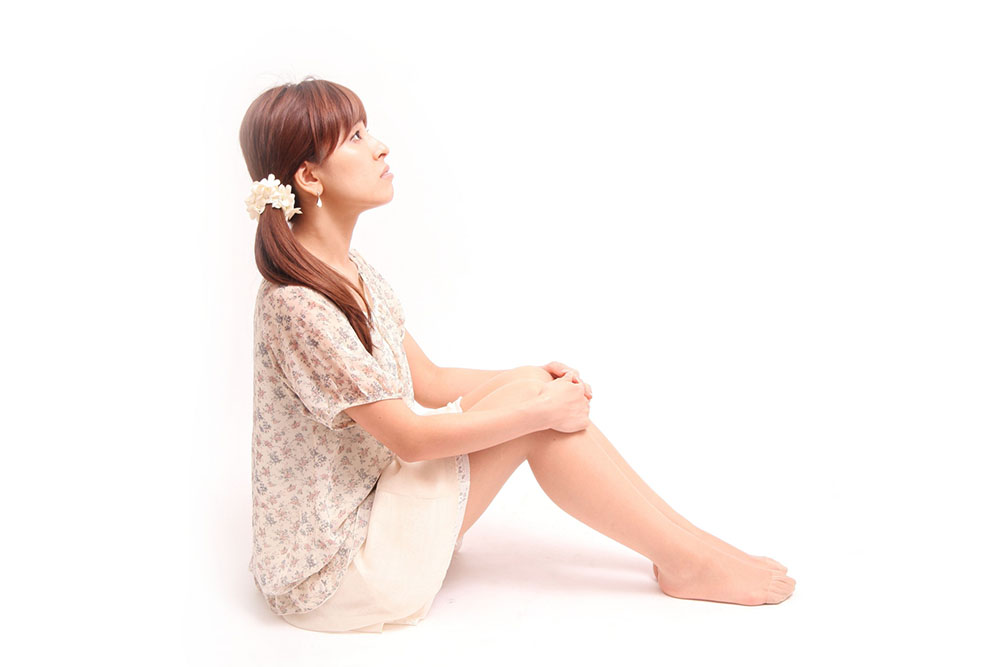 体育座りで上を見上げる女性