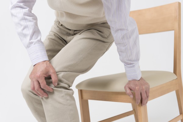 イスに手をつき座ろうとする年配の男性