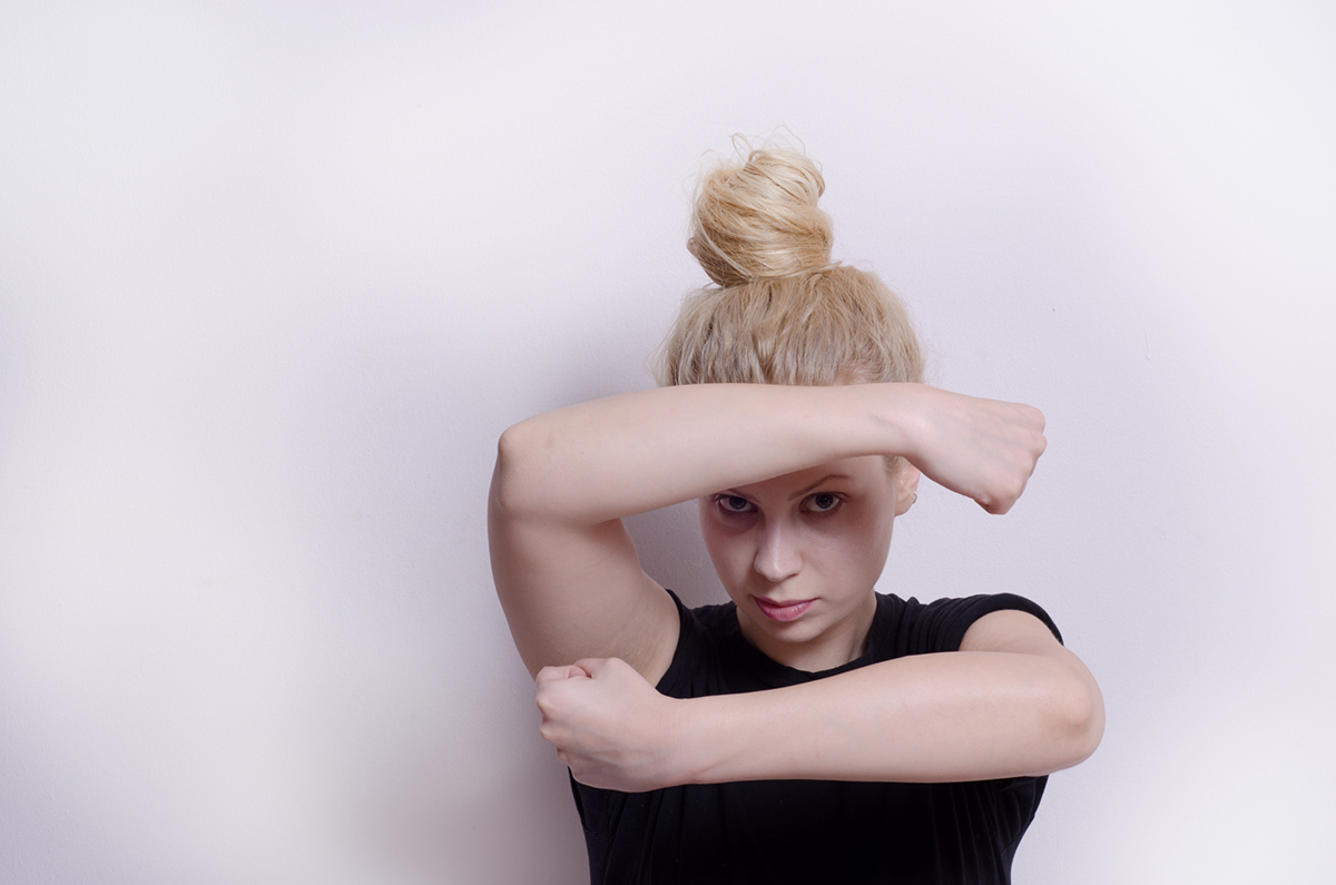 肘を曲げグーを握り顔の前にかざす女性