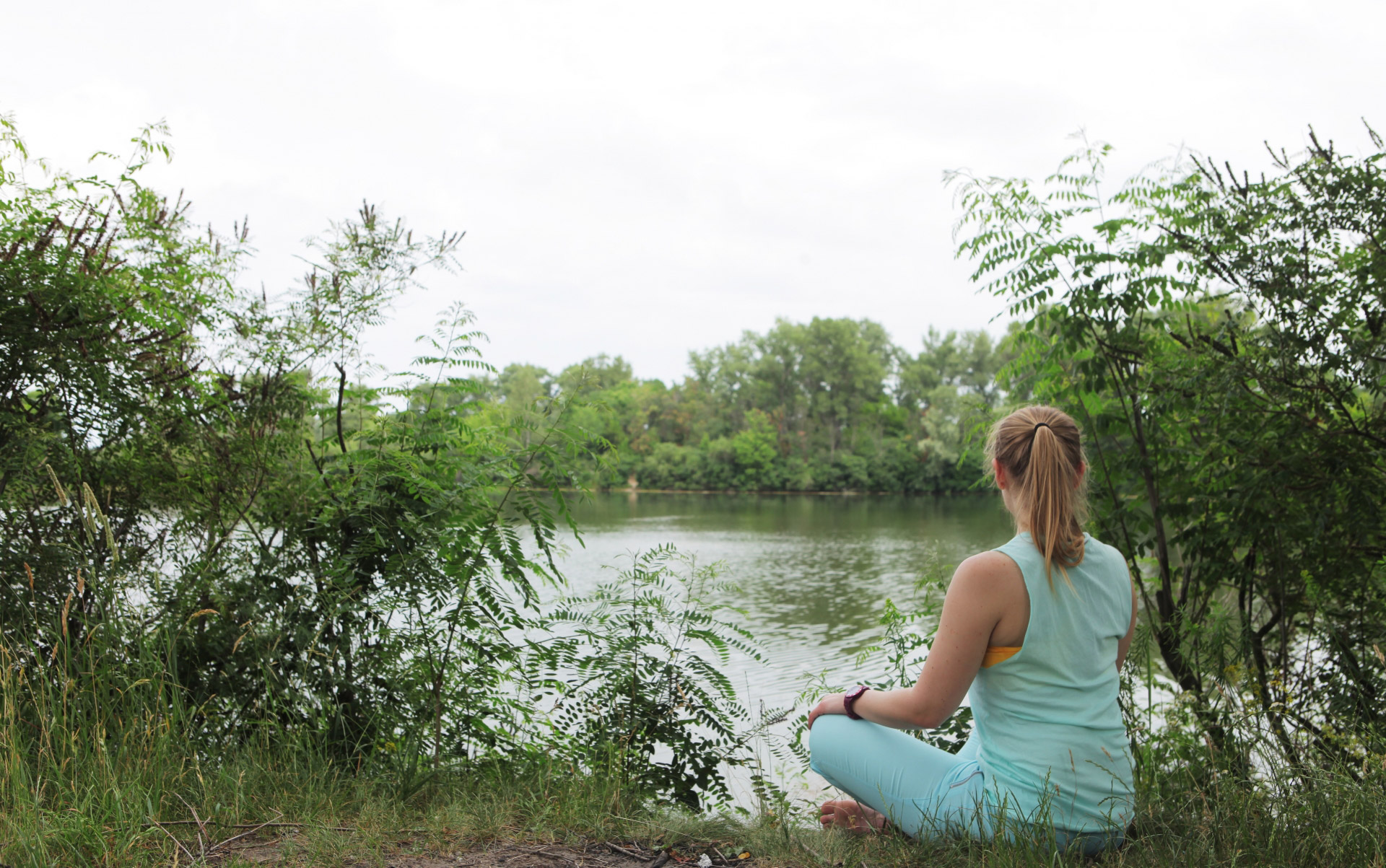 瞑想のポーズをし池を眺める女性