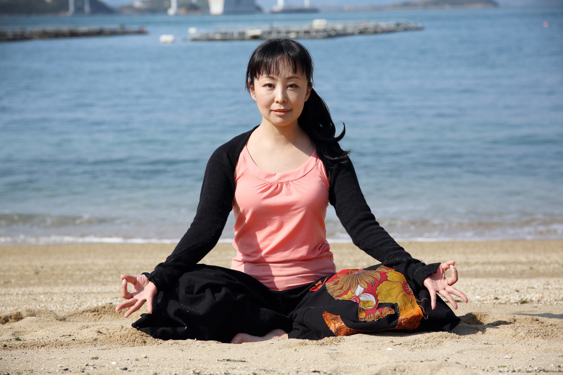 海岸で瞑想のポーズをする女性