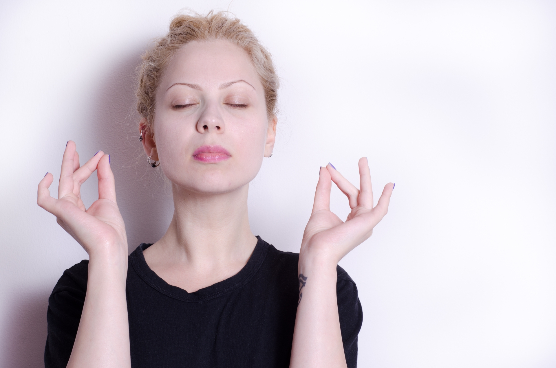 親指と中指を付け目を閉じる女性