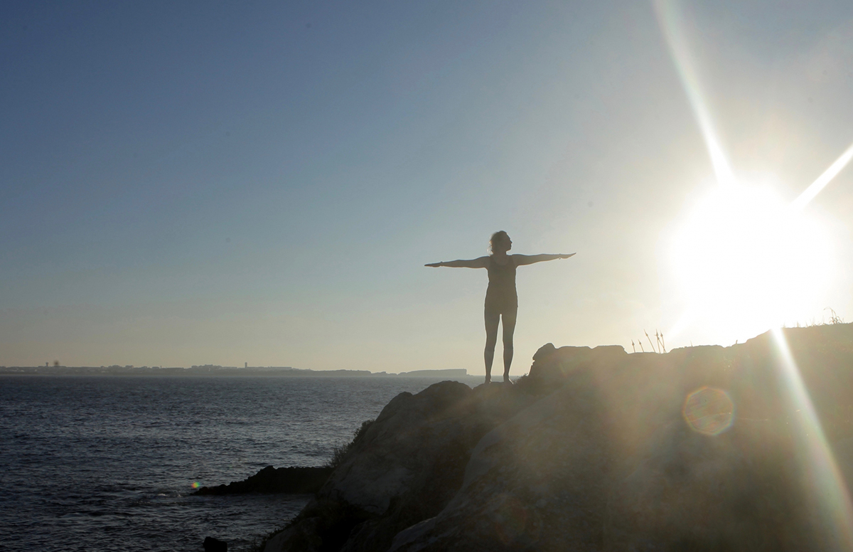 海岸で腕を一直線に伸ばす女性