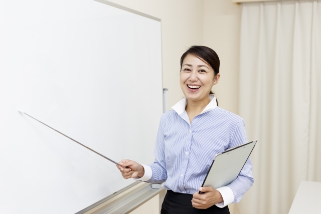 ホワイトボードを棒でさす女性
