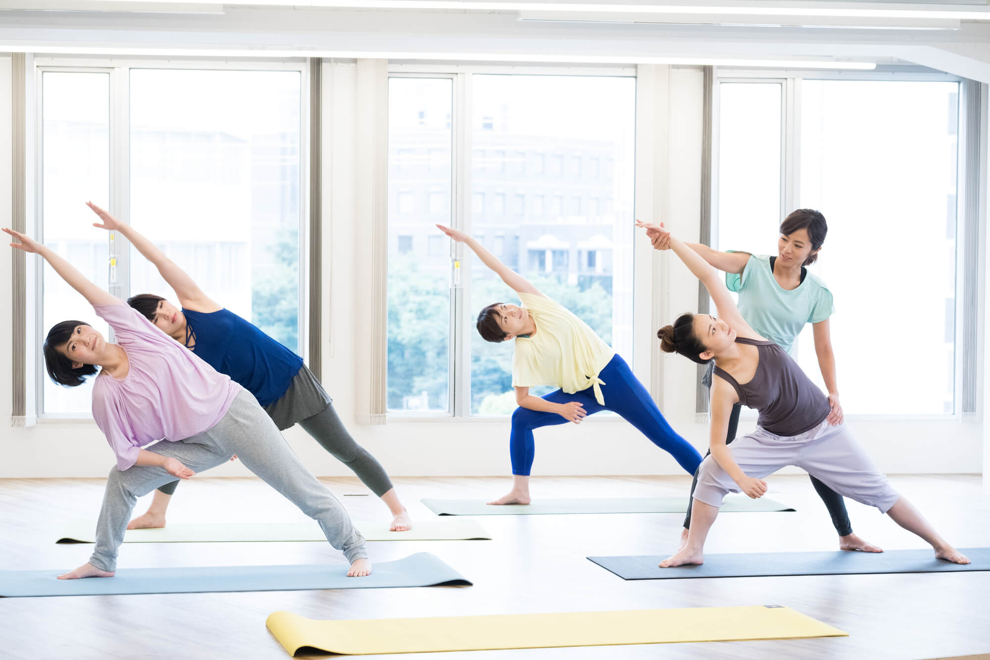 ヨガのポーズを教えるエデュケーターとレッスンを受ける女性たち