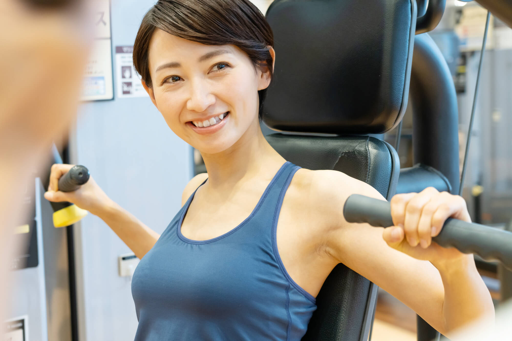 マシンで筋トレをする笑顔の女性