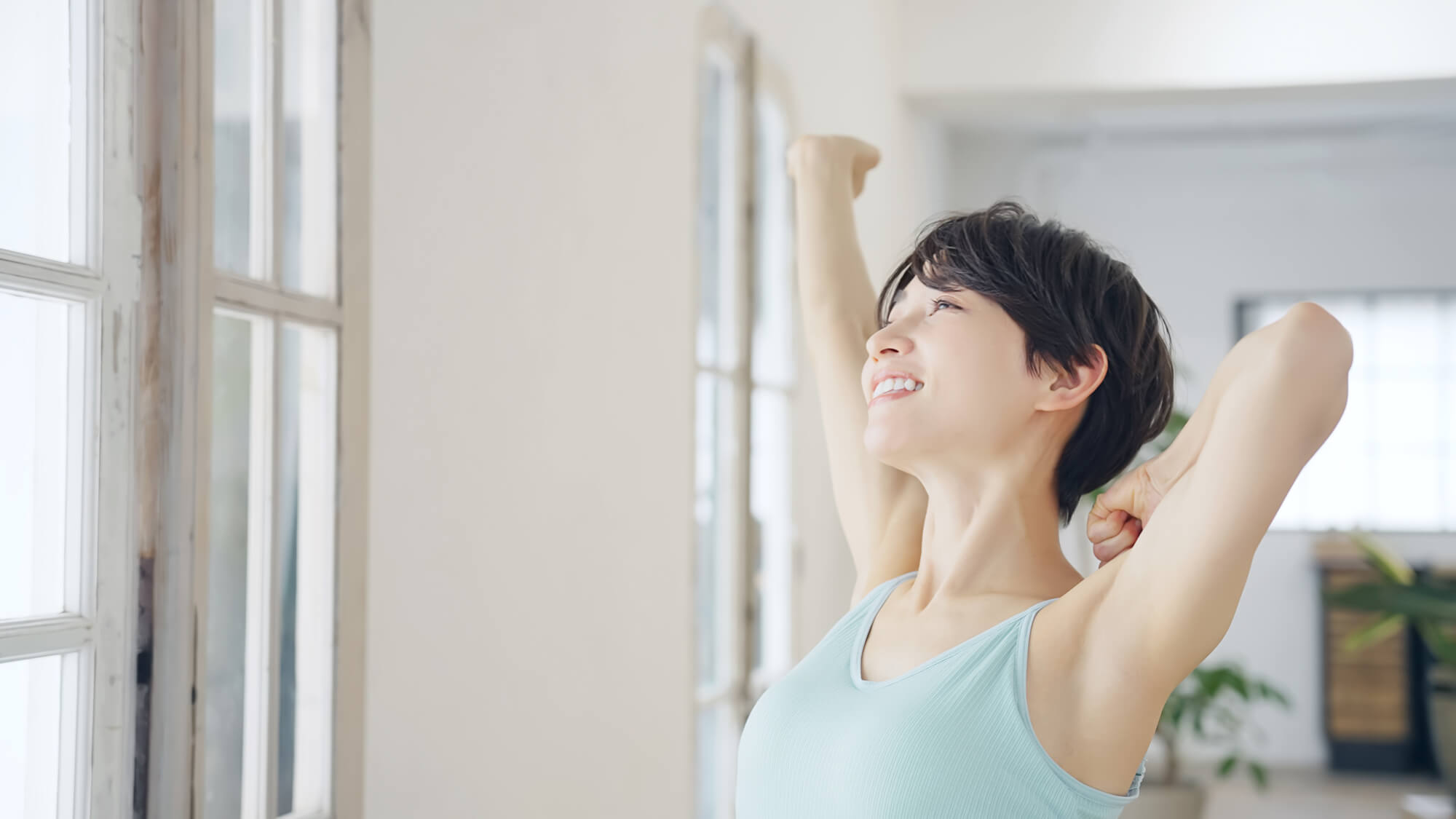 窓際で伸びをする女性