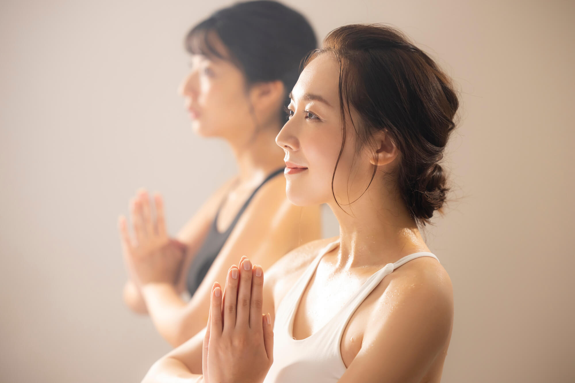 胸の前で手を合わせる2人の女性