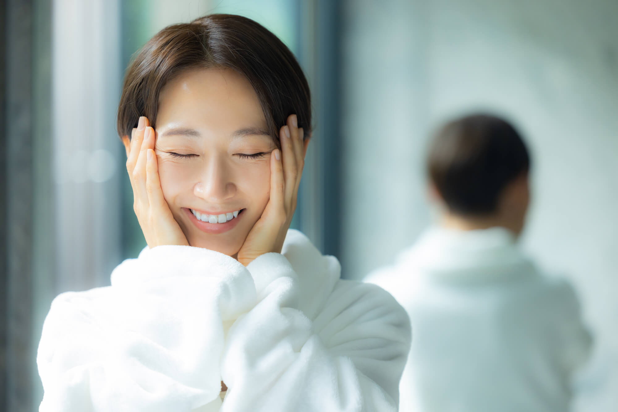 両頬を手で包み込む笑顔の女性