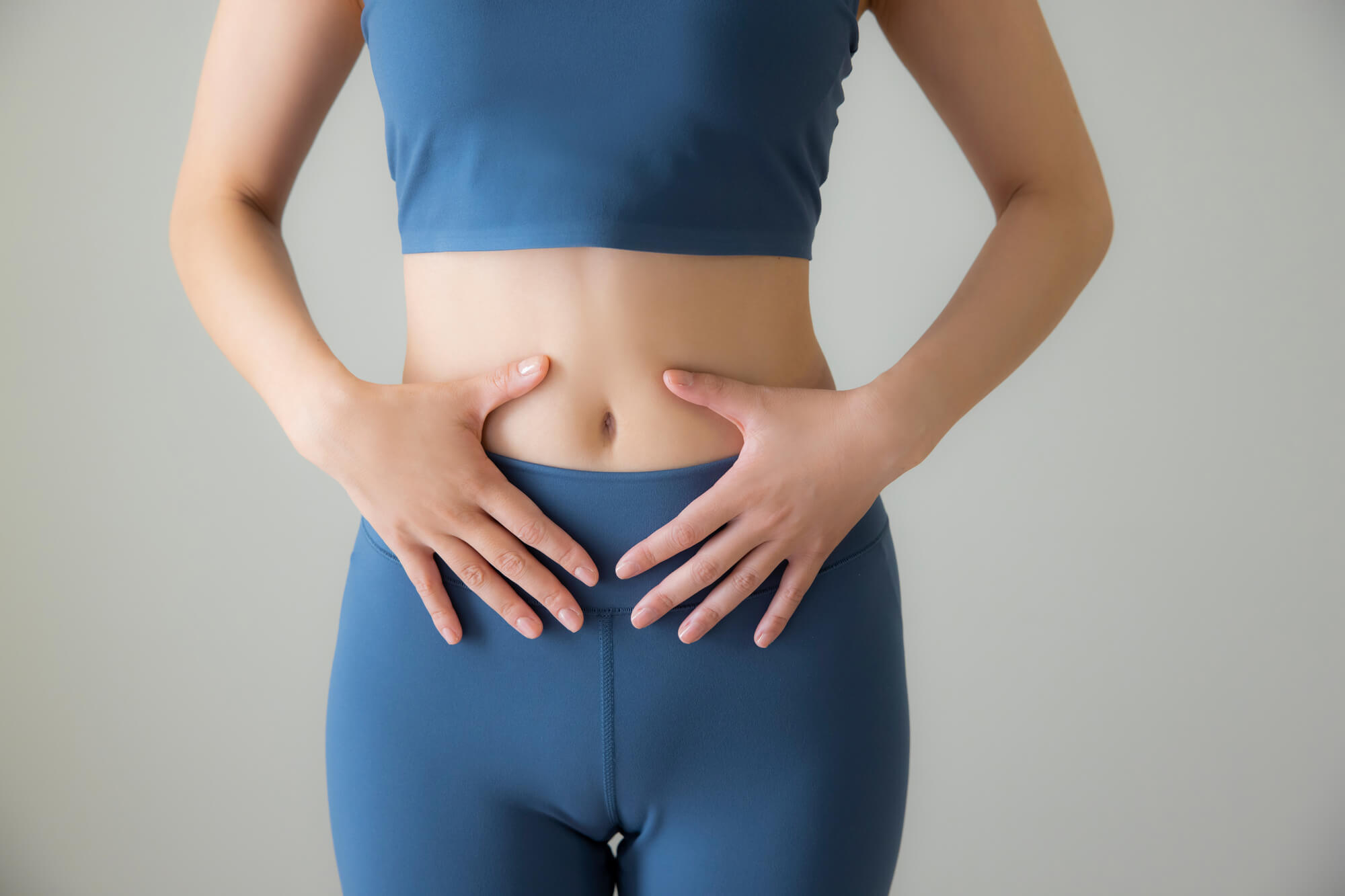おなかに手を当てるスポーツウェアの女性