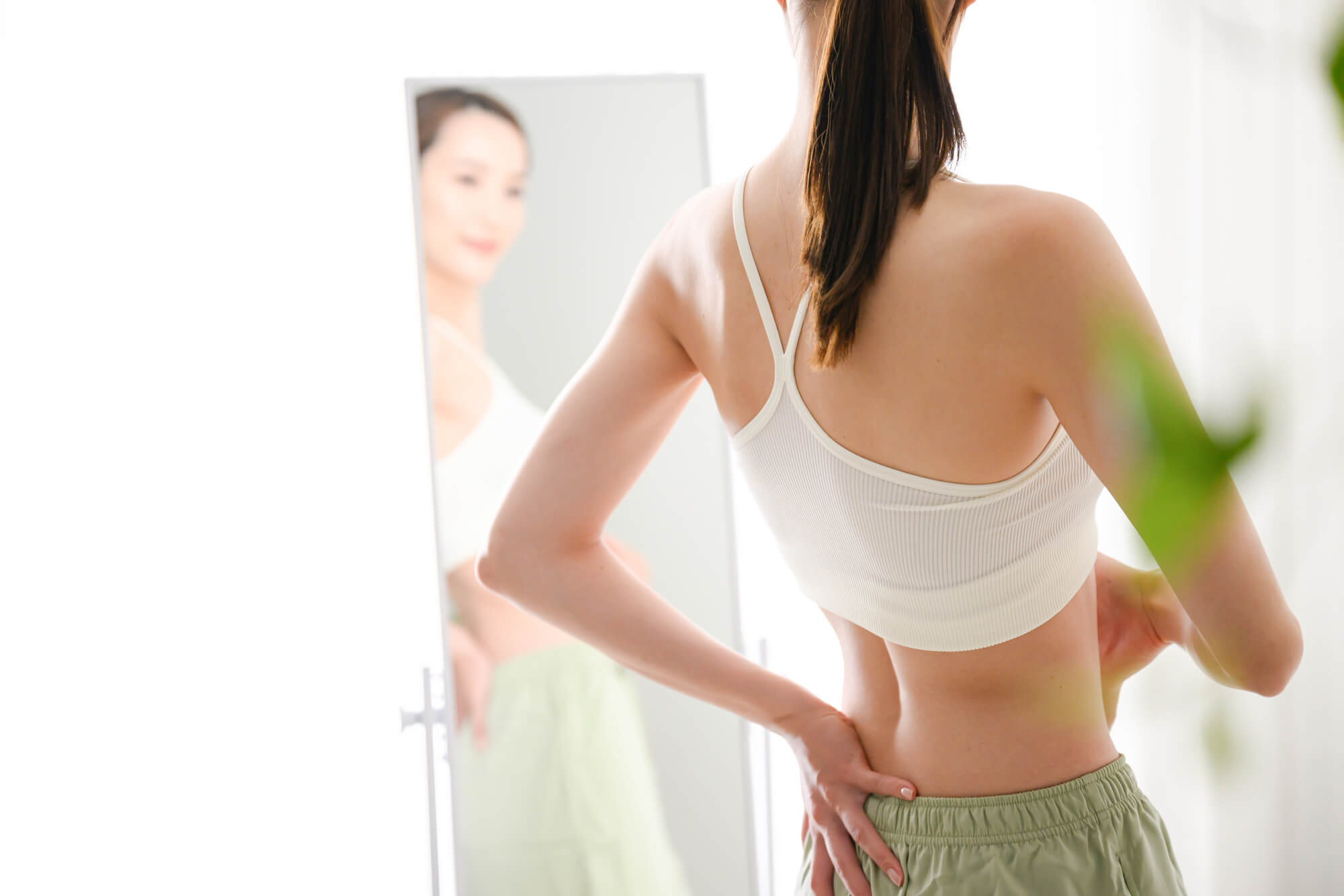 鏡の前に立ち、ウエストをチェックする女性