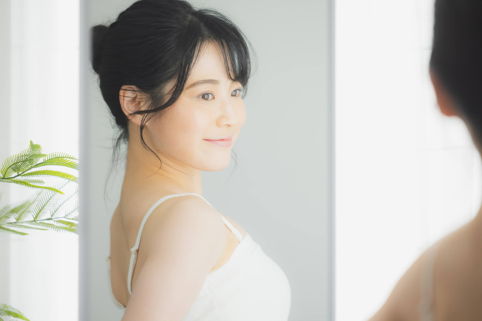 鏡の前で背筋を伸ばす女性