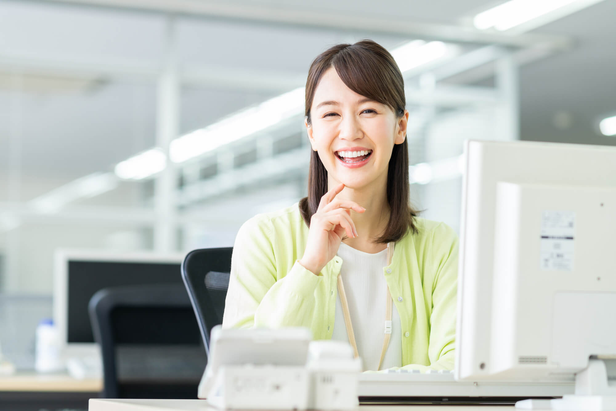 オフィスのパソコンの前で、楽しそうにほほ笑む女性