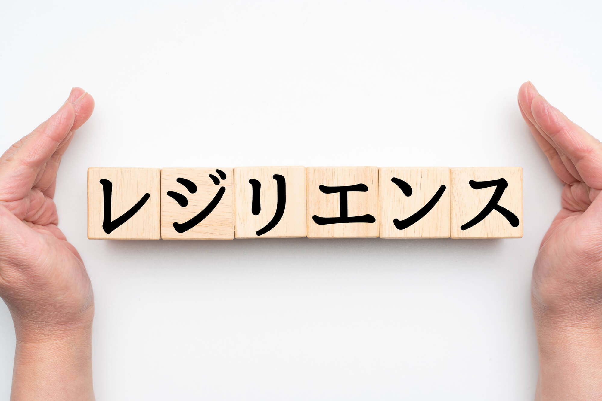 レジリエンスと書かれた積み木と、それを囲うように置かれた両手