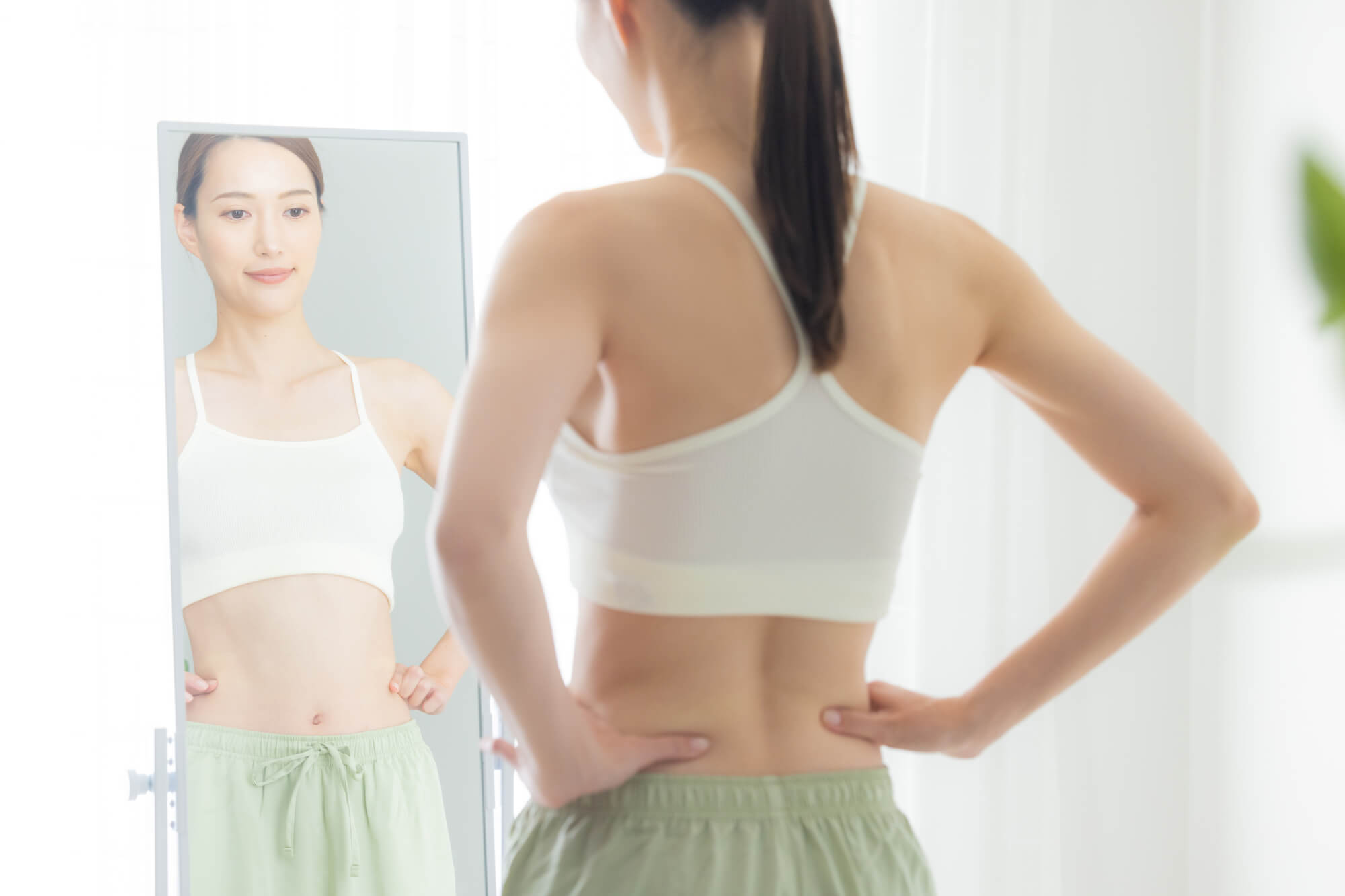 全身鏡に向かって立ち、ボディチェックをする女性