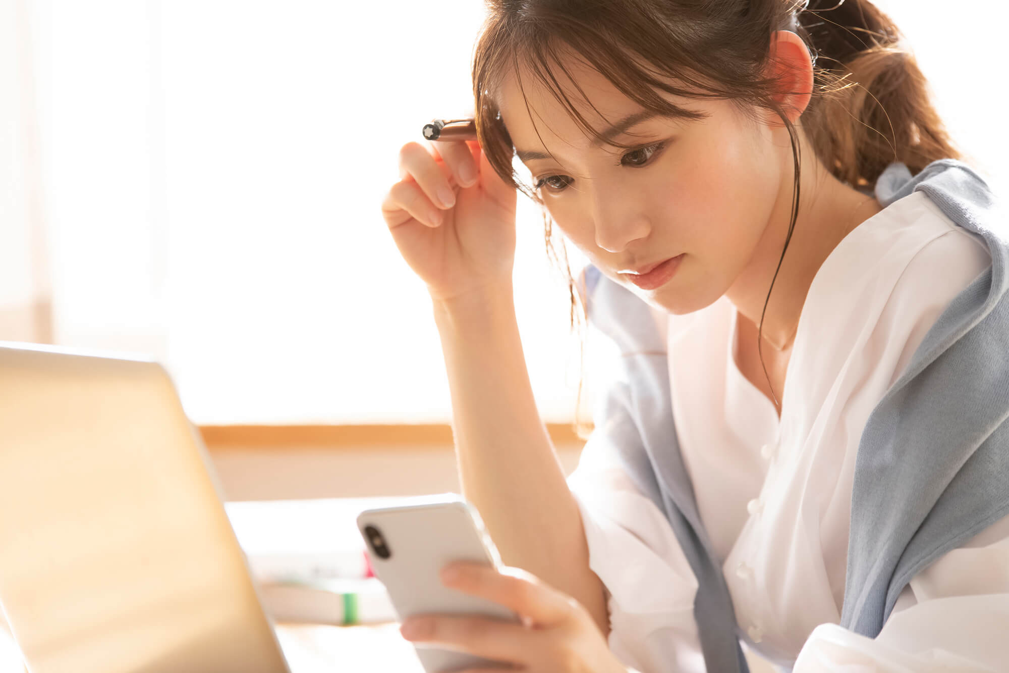 片手に持ったスマホを見ている女性