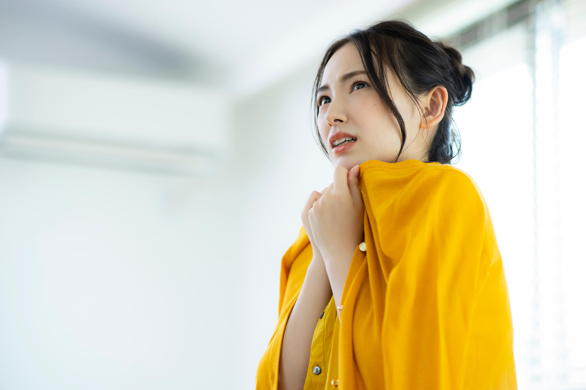 冷房の効いた室内で寒さに震える女性