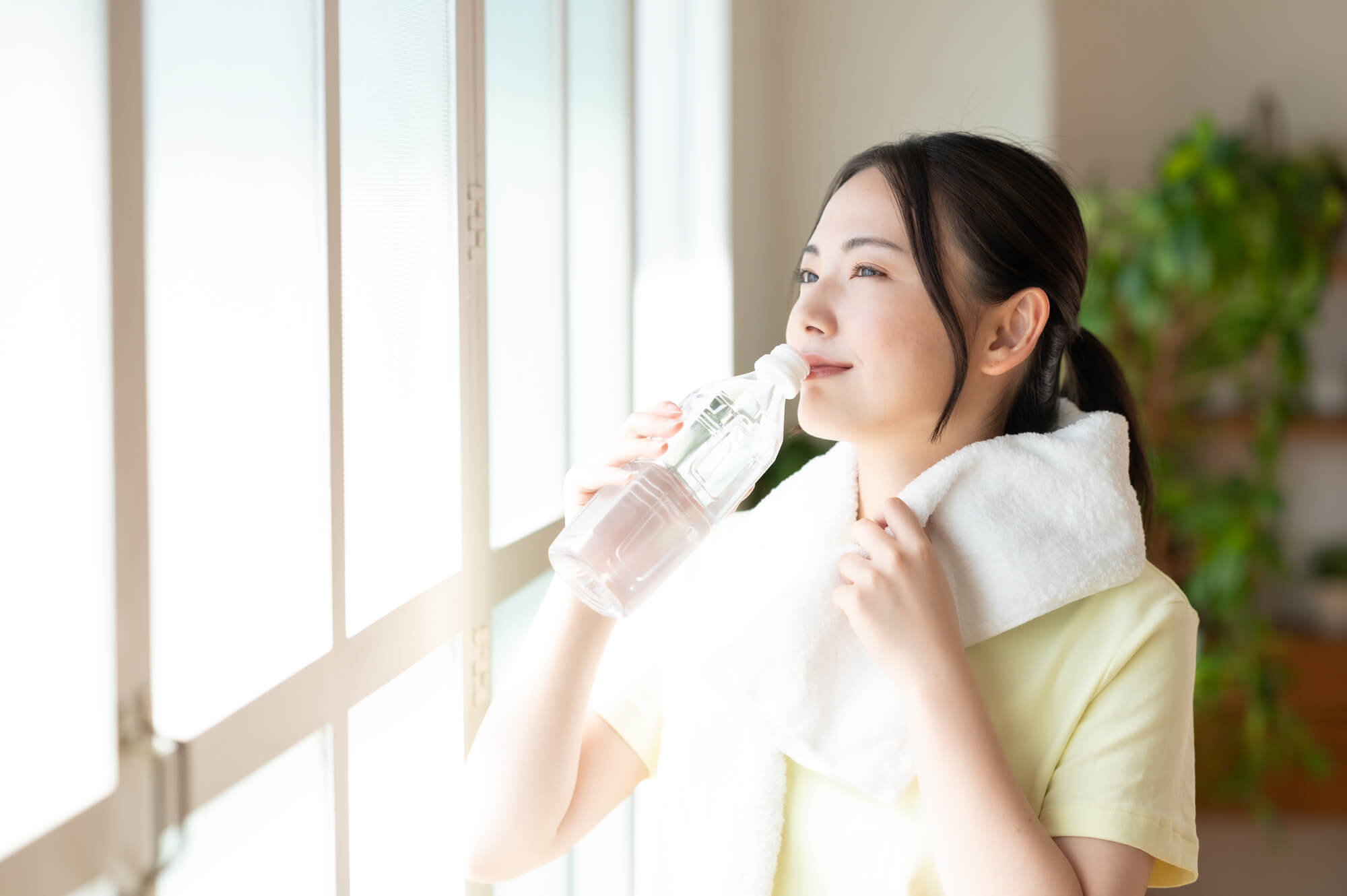 首にタオルを巻いて水分補給をする女性