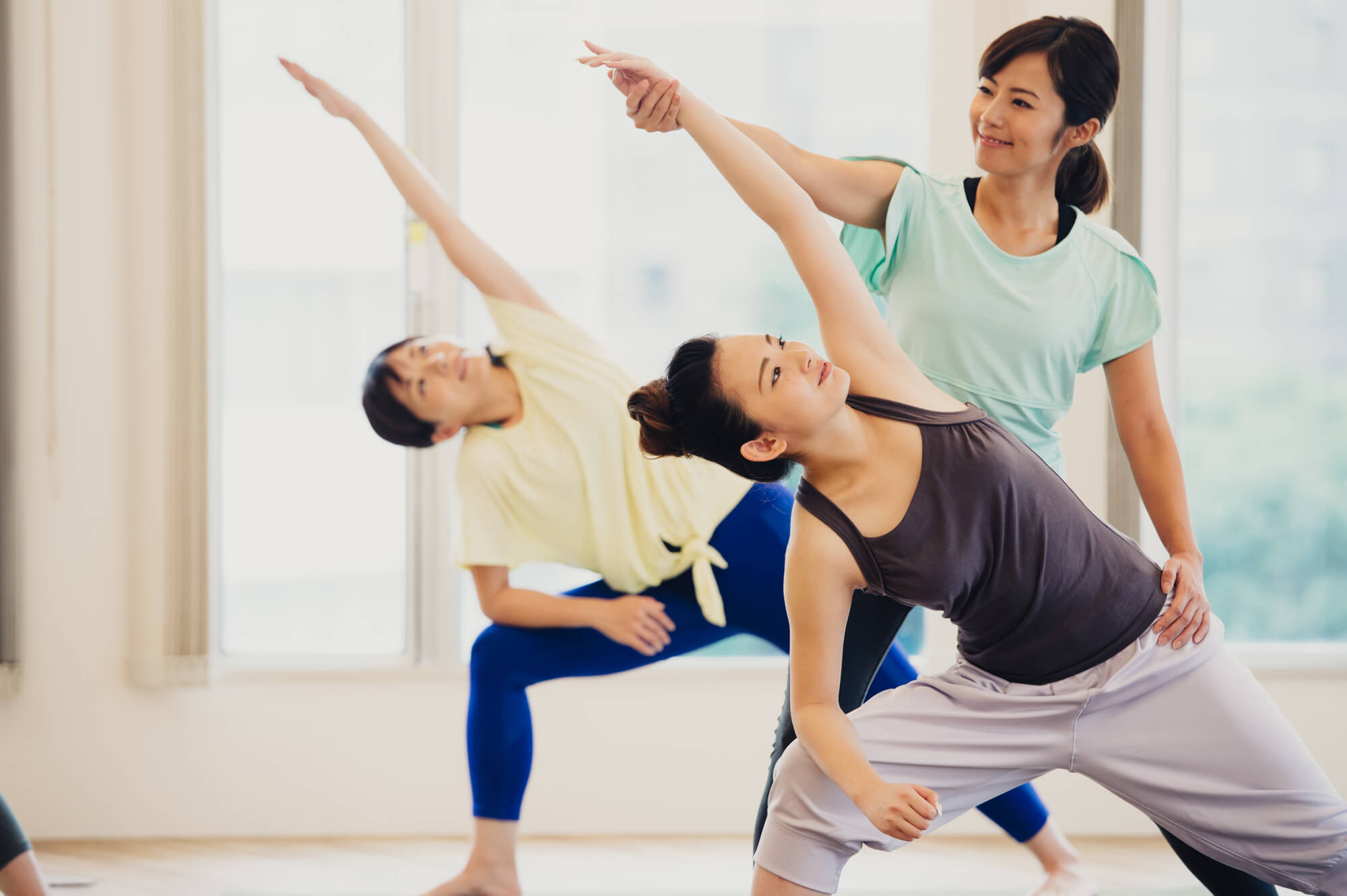 ヨガを行う2人の女性とヨガを指導する女性