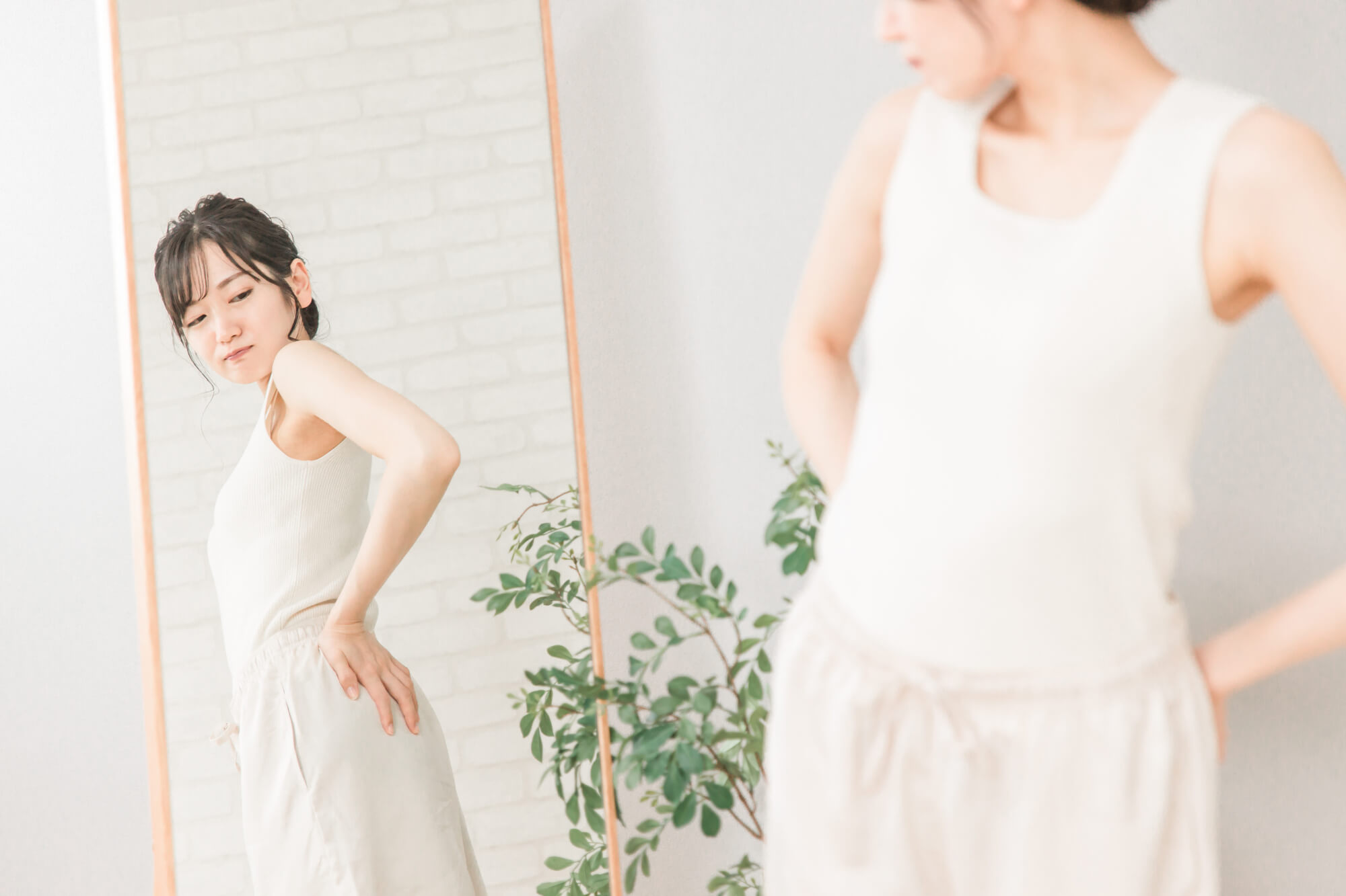鏡を見ながら腰の辺りを気にする女性