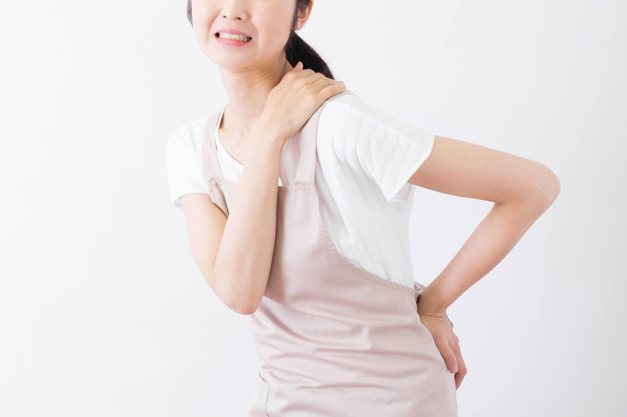 腰と肩を抑えながら痛そうな表情を浮かべる女性
