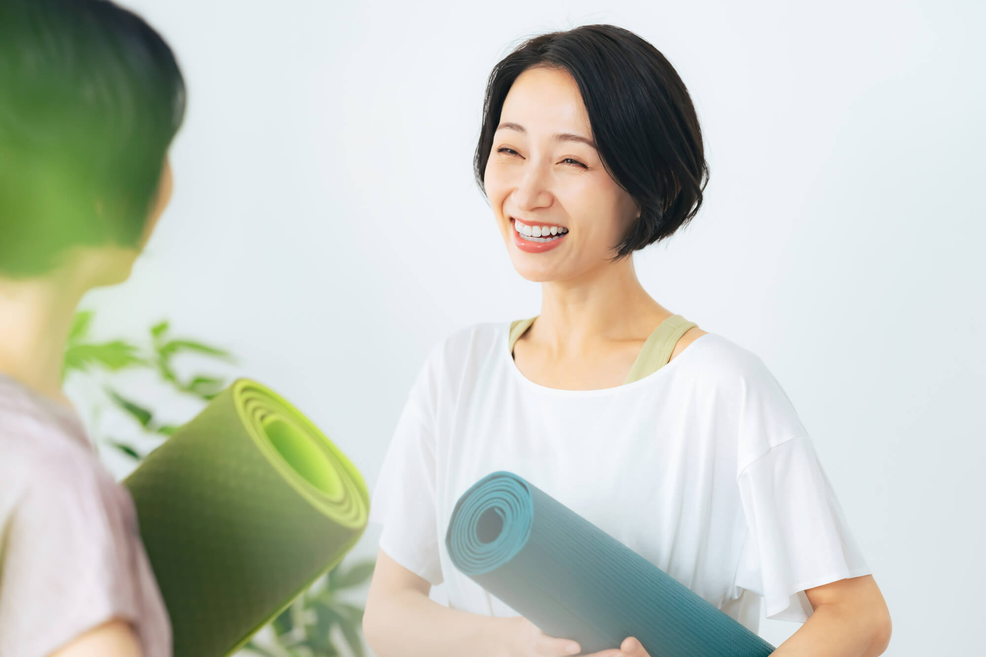 ヨガマットを持ちながら談笑する女性2人