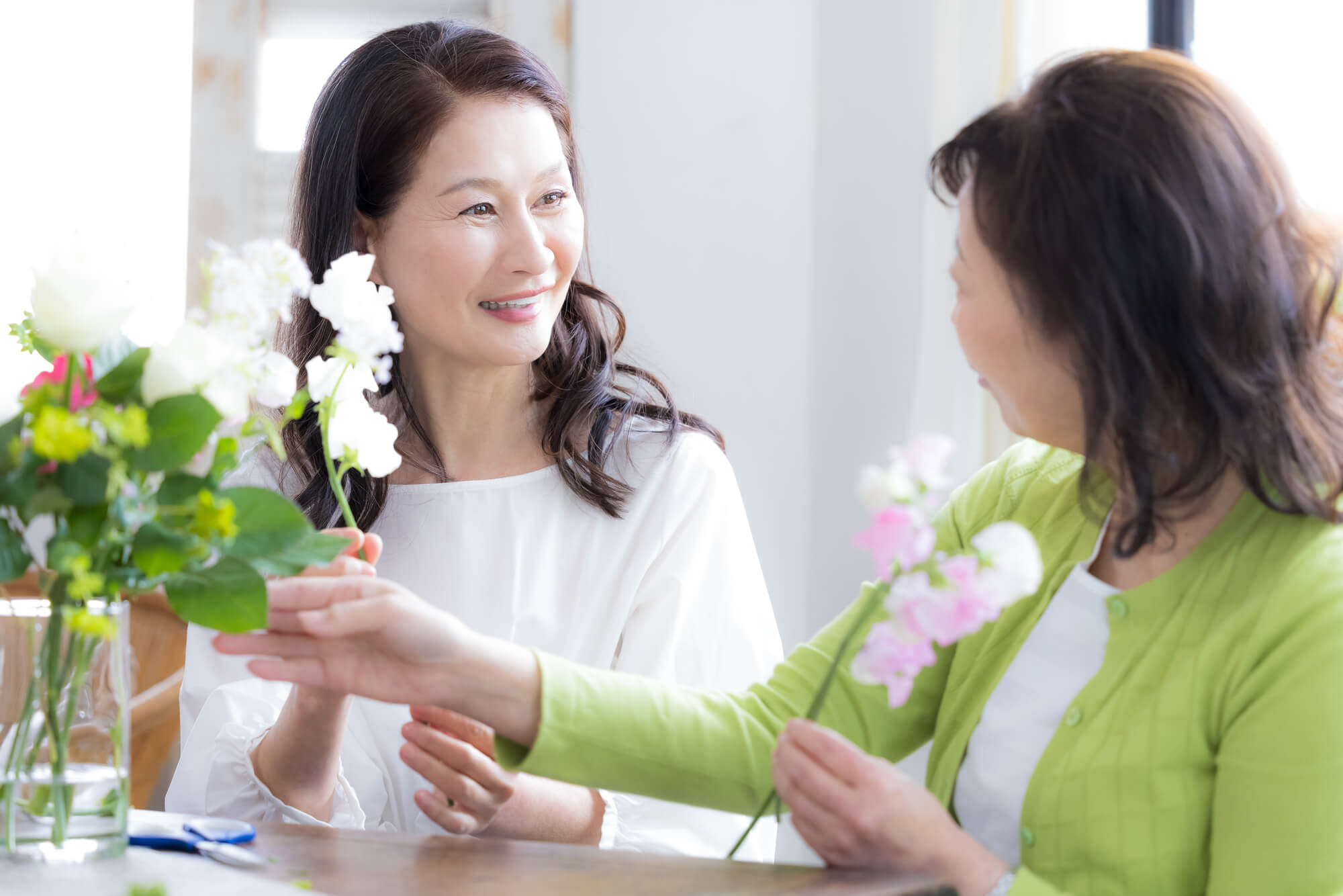 花を生けながら談笑する女性2人