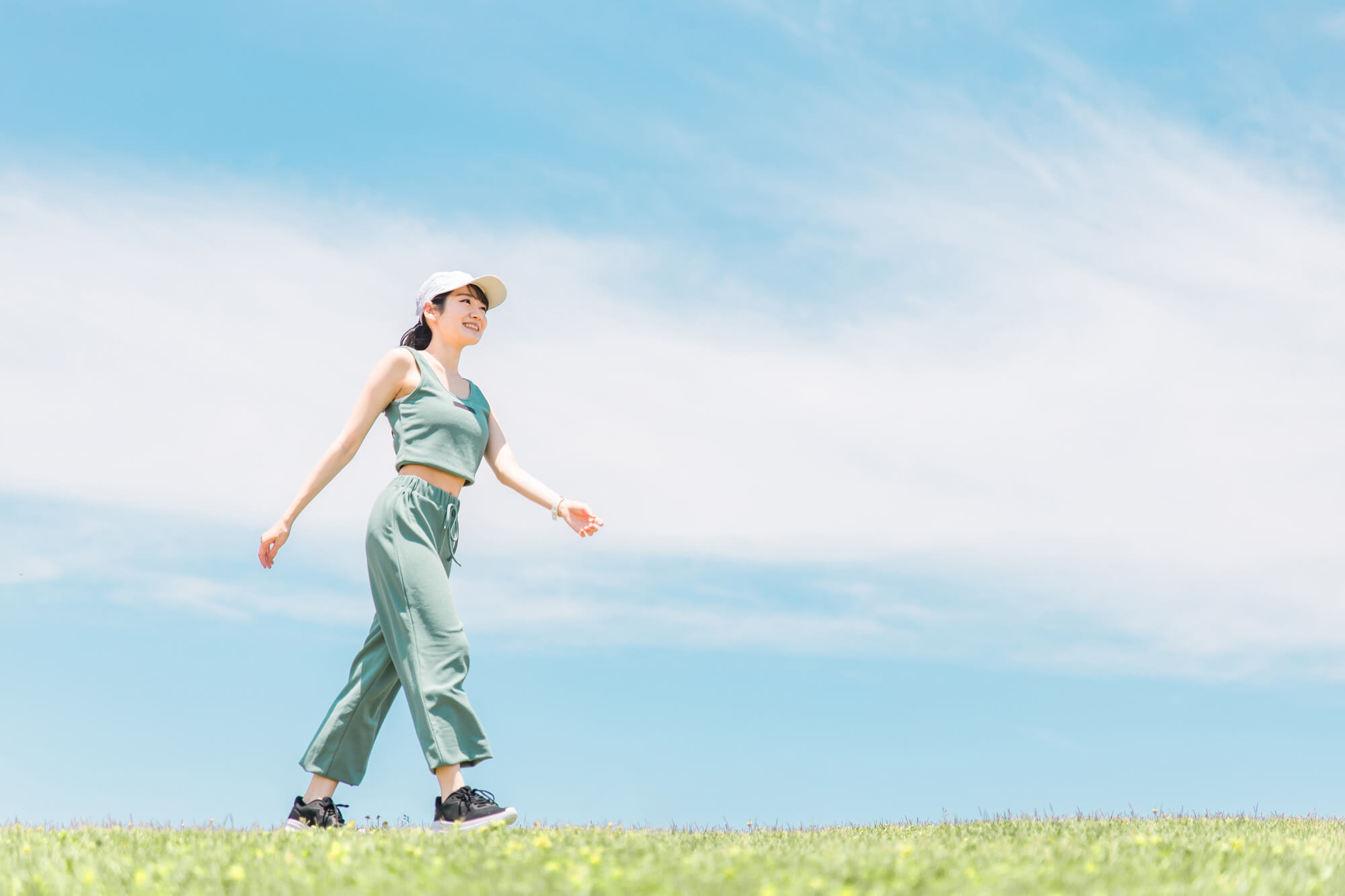晴れた日に芝生の上を笑顔でウォーキングする女性