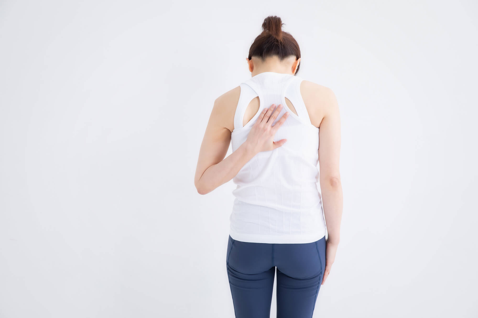 肩を落とし背中を押さえる女性の後姿