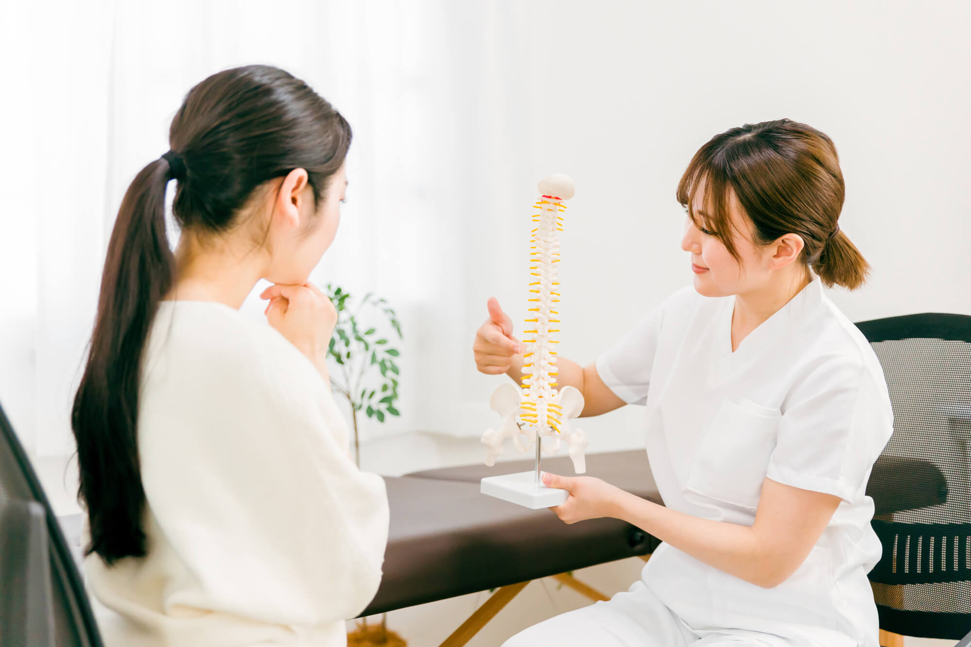 骨盤の模型を持ち説明をする女性と考え込む女性