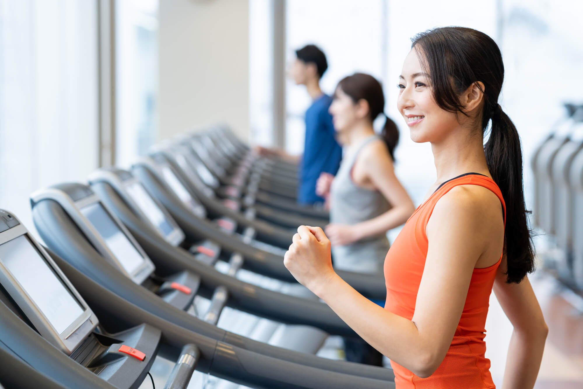 ジムでルームランナーをする笑顔の女性