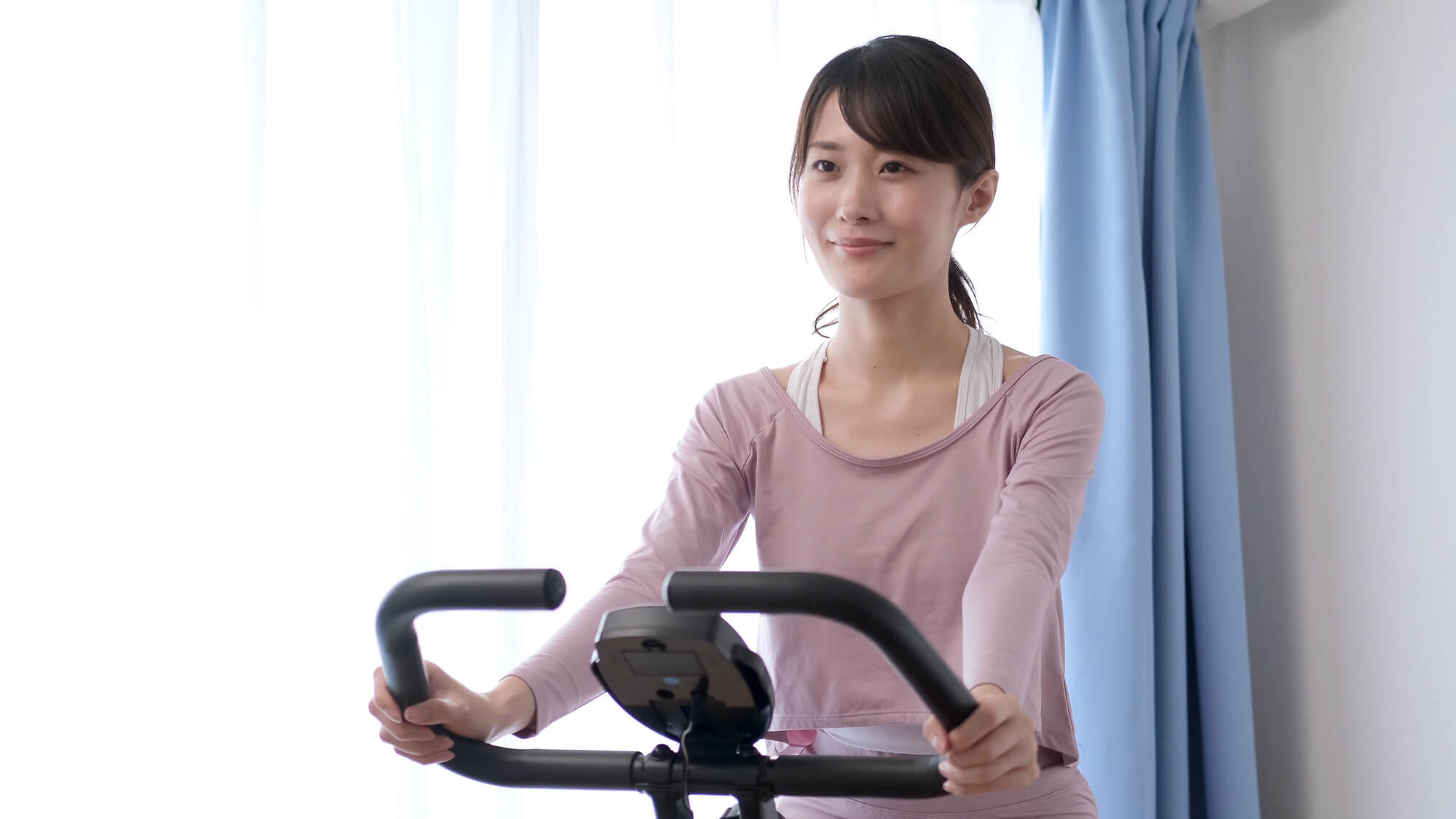 室内でエアロバイクをこぐ女性