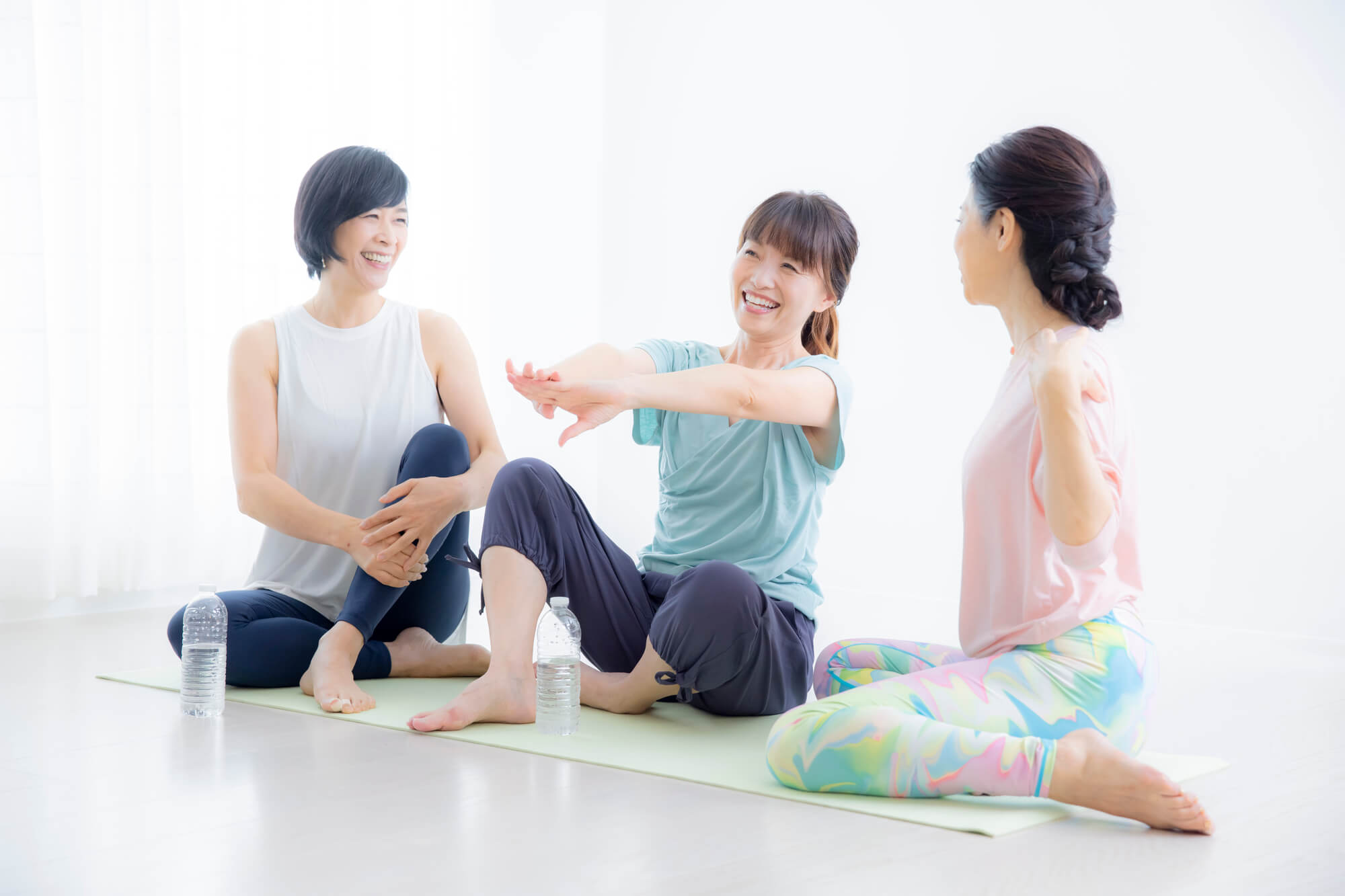 ヨガマットの上で談笑する3人の女性