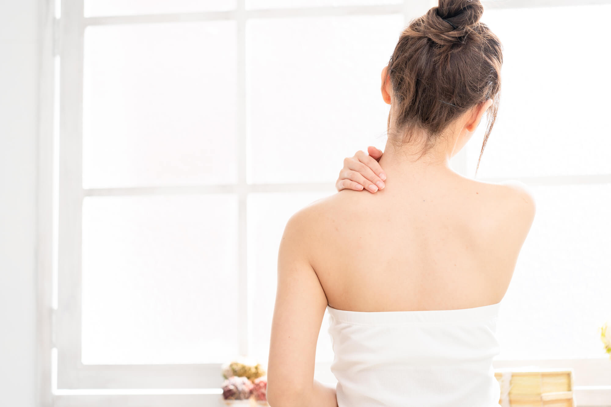 肩に手を当てる女性の後ろ姿