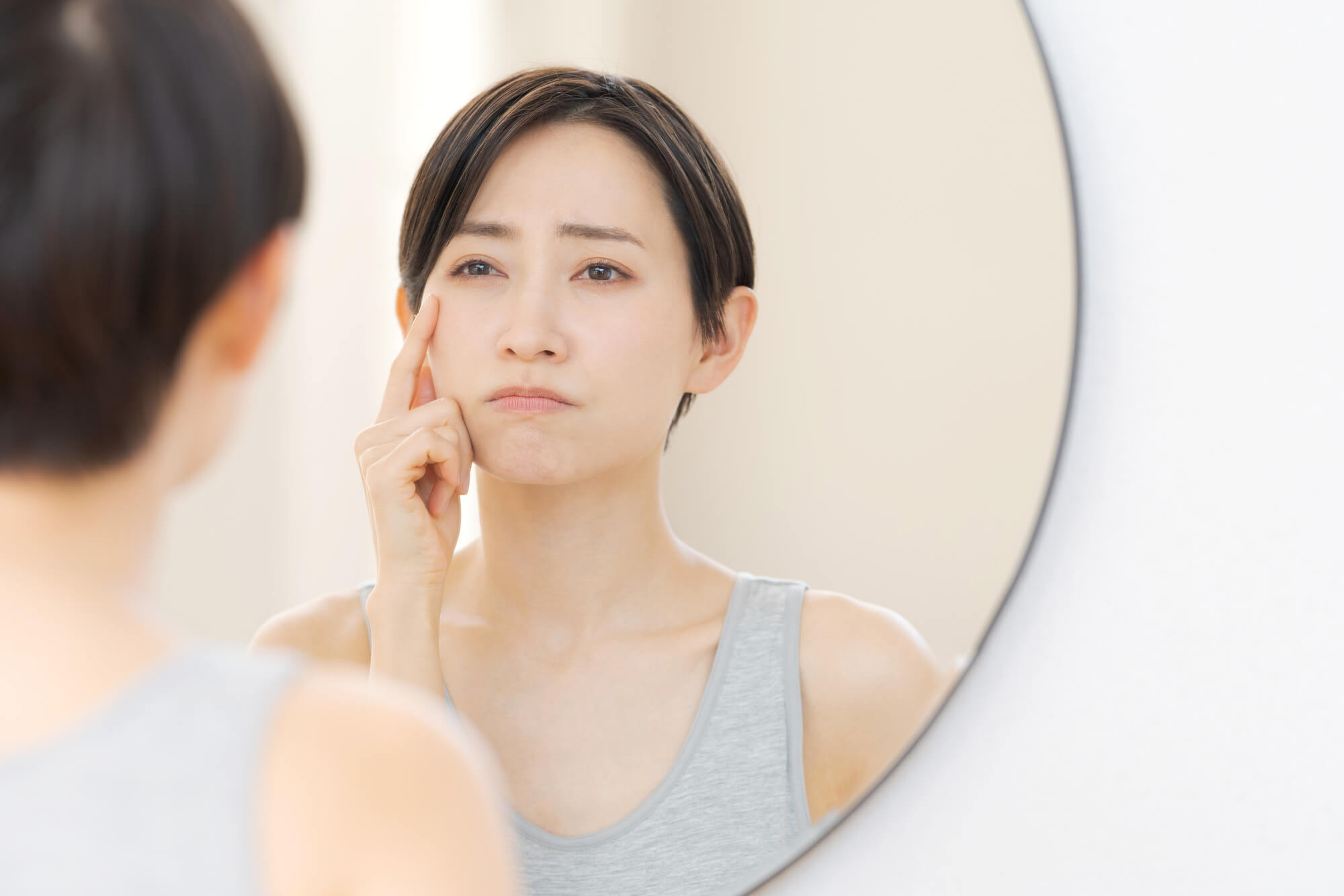 鏡に映る自分に悩む女性