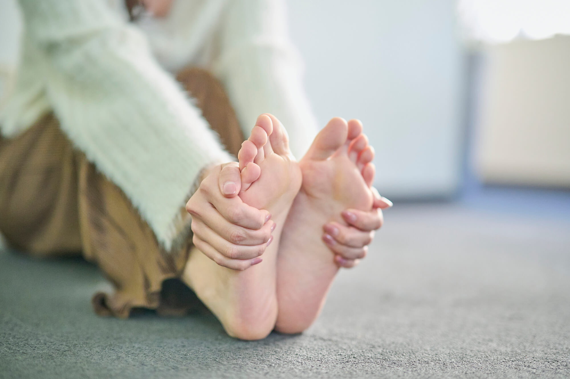 自分の足裏を触る女性