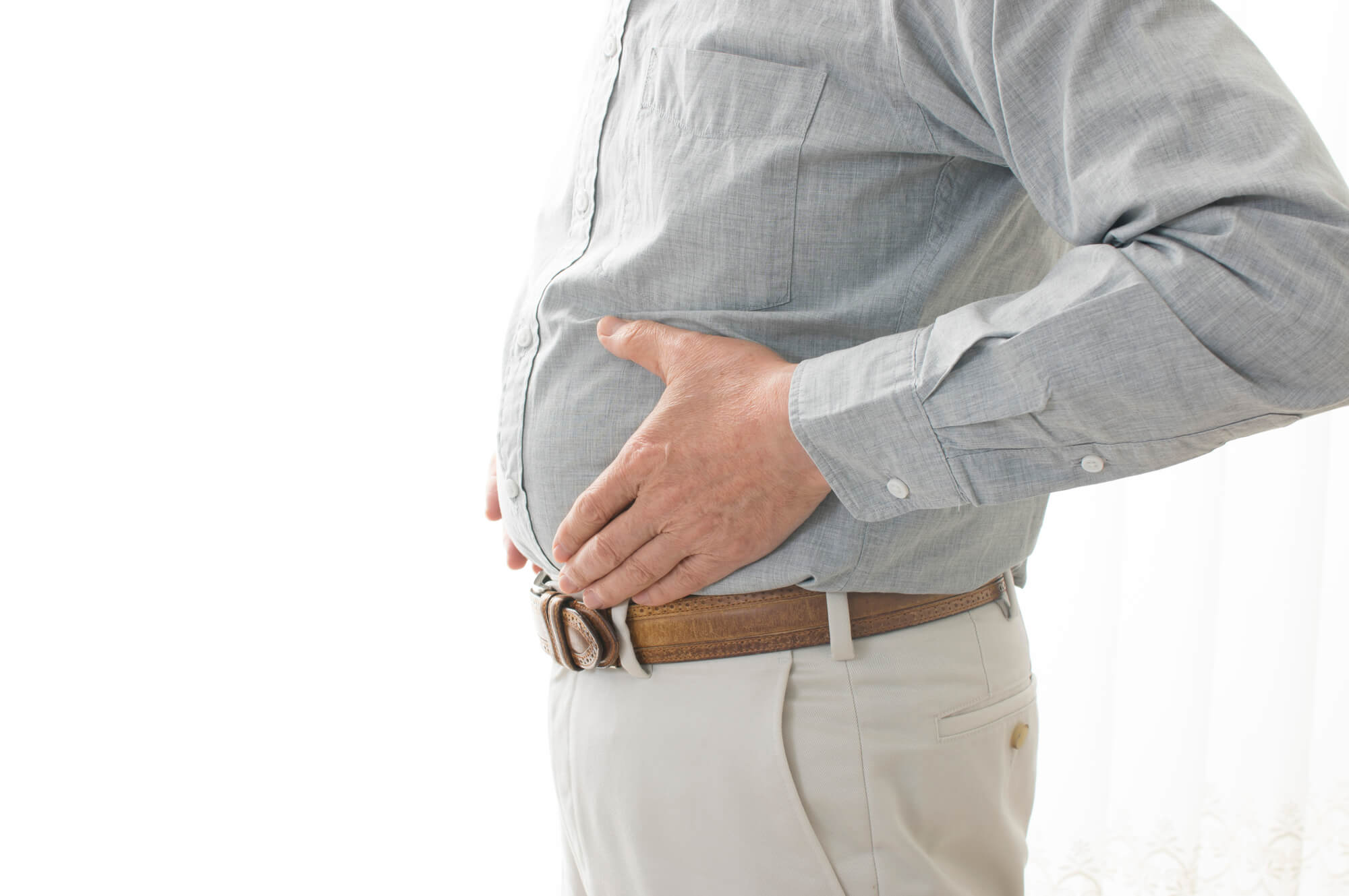 ぽっこりとしたおなかをおさえる男性