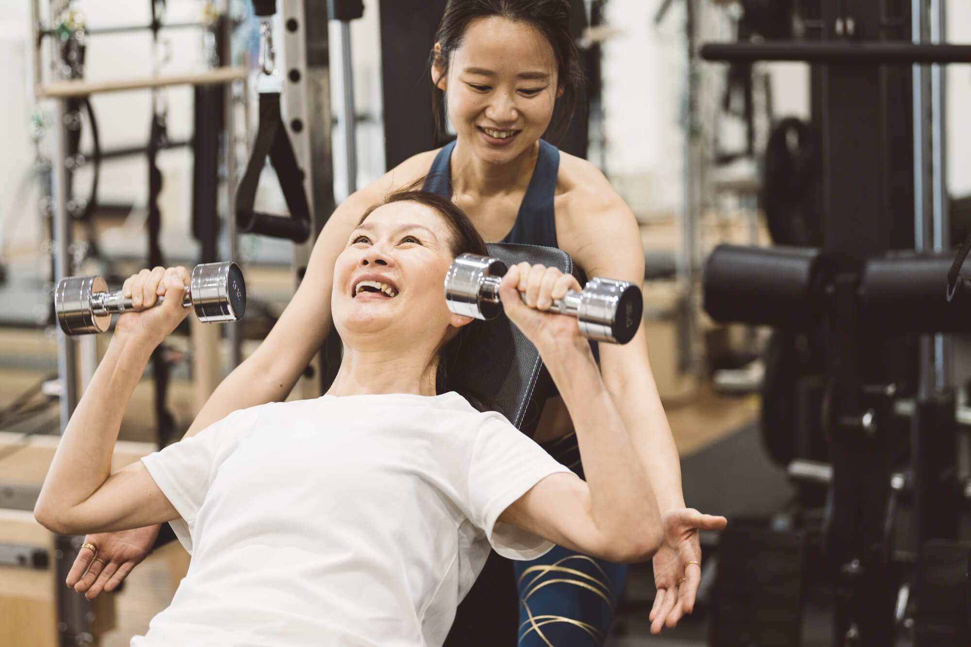 笑顔で筋トレに励む女性とやり方を教える女性