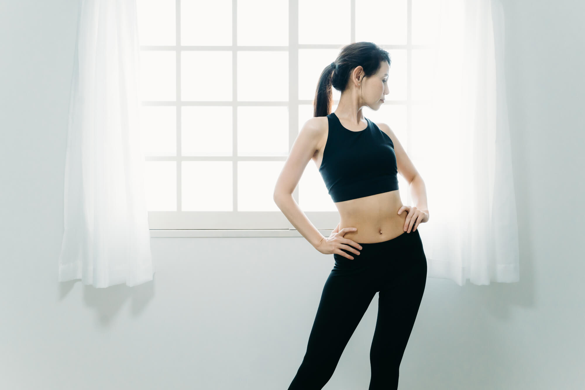 窓際に立つ引き締まったスタイルの女性